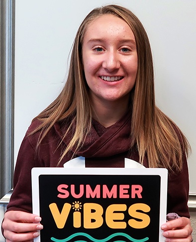 Young woman holding a sign reading summer vibes after finishing her orthodontic treatment